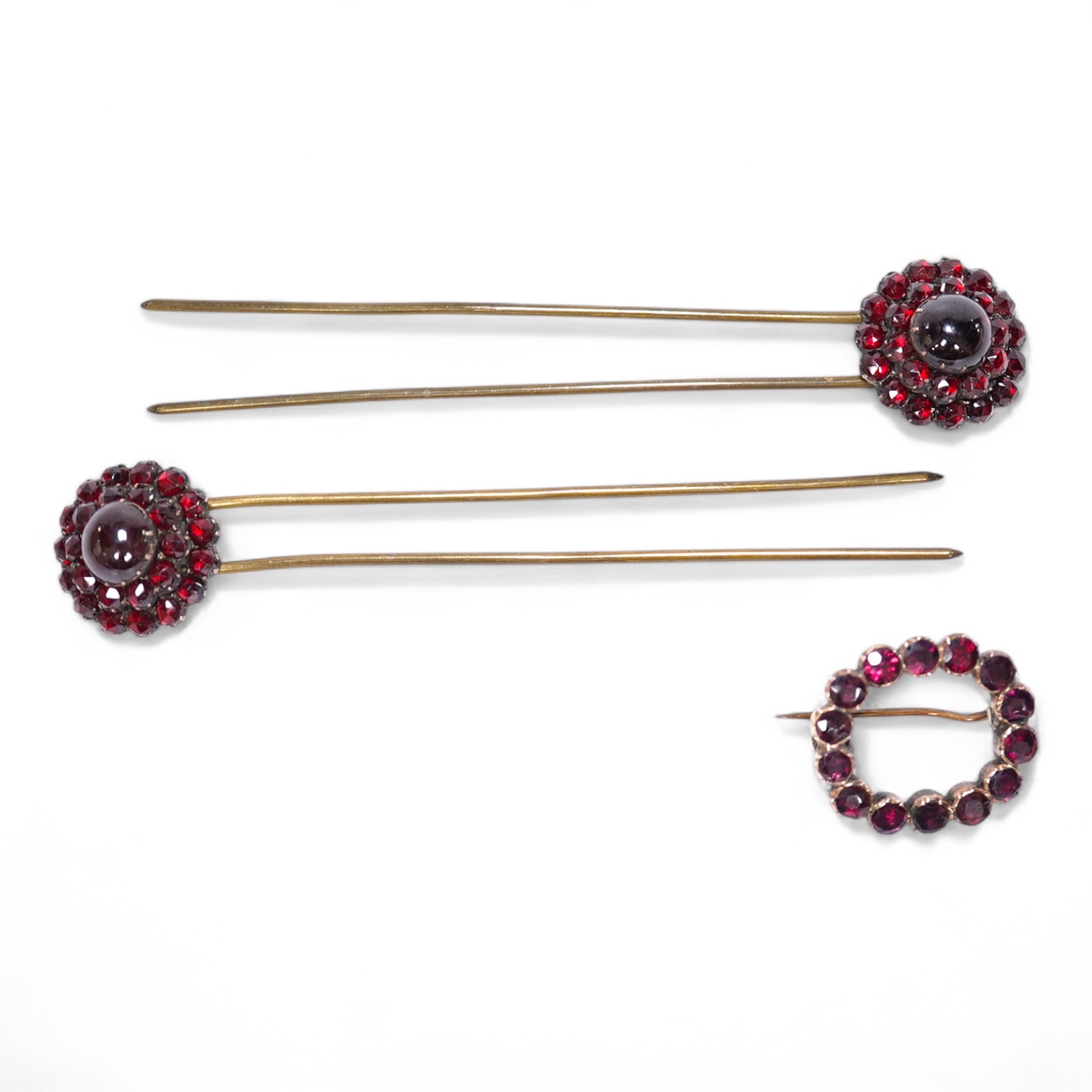 A Victorian yellow metal and garnet cluster set open work brooch, 27mm, together with two garnet cluster set hair ornaments. Condition - poor to fair